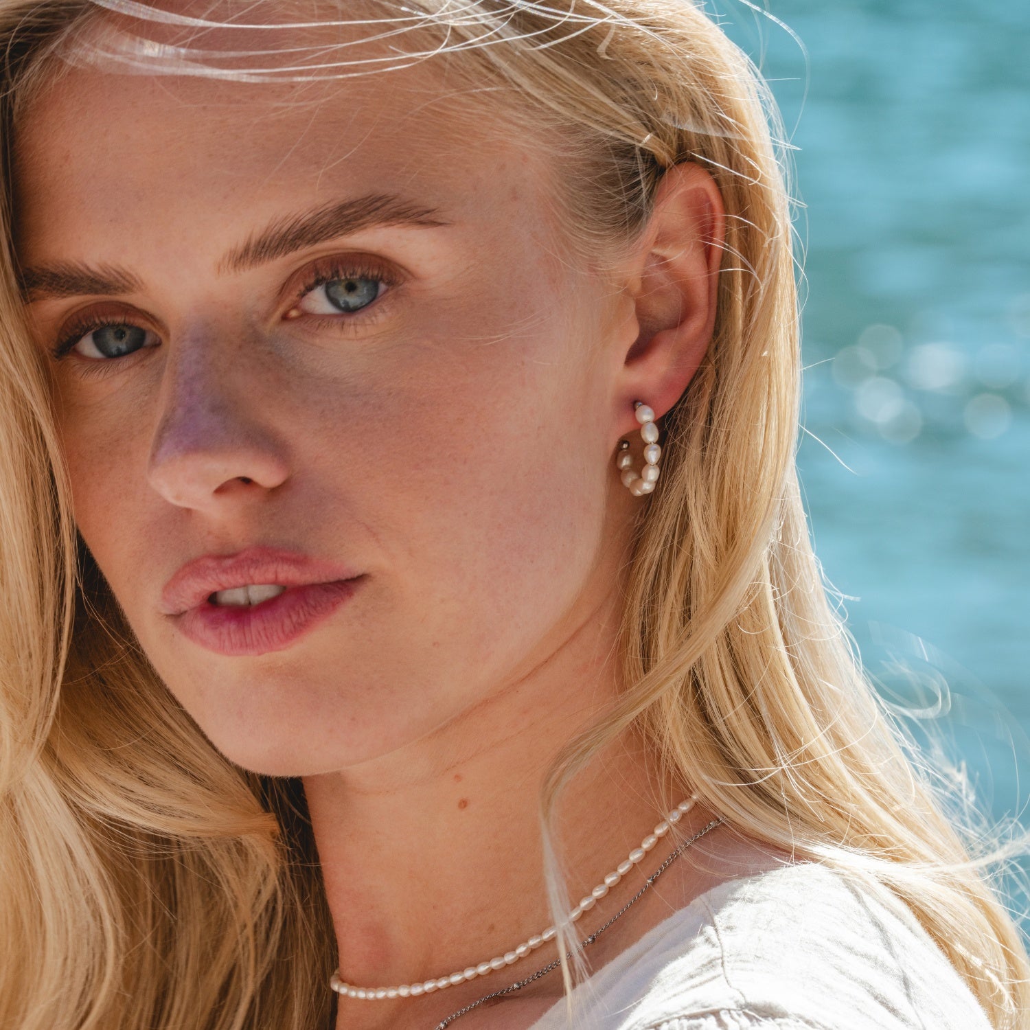 Silver Cala Pearl Hoops styled in summer lifestyle setting